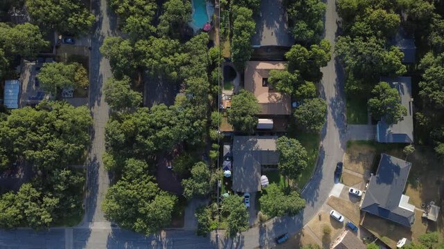 Curved residential lanes terminate into quiet suburban dead ends near Little Bear Creek. Shaded house roofs, parked vehicles, backyard swimming pools reveal serene neighborhood design, Hurst, TX
