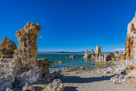 Jagged limestone tufa formations line the shore of Mono Lake under a clear blue sky.