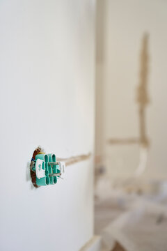 Exposed electrical socket mechanism protrudes from an unfinished wall opening