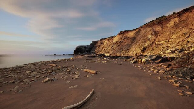 golden cliff beach at sunset, warm glow on sandstone and driftwood, gentle waves lapping, secluded mood for travel and landscape portfolios, ideal
