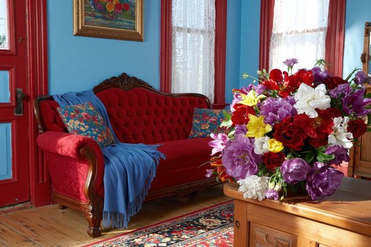 Vintage revival in interior design, living room with red sofa, colorful pillows and a flowers