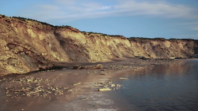 sunset cliffs with reflective tide pools, scattered limestone boulders glisten in warm amber tones, calm water mirrors sky, scene fits coastal decor and social