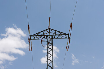 Obraz premium Electricity transmission pylon supporting power lines in blue sky