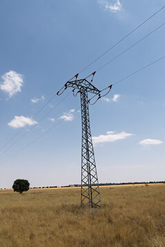 Electricity pylon transmitting power lines across rural field