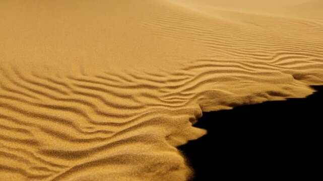 Golden sand dune showing rippled texture beside a dark empty area in close view