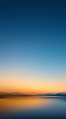 Obraz premium Calm Horizon: A serene landscape photograph captures the tranquil beauty of a clear horizon where a vibrant sunset meets the calm water, reflecting a breathtaking gradient of orange and blue.