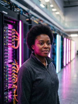 Female technician in illuminated data center server room