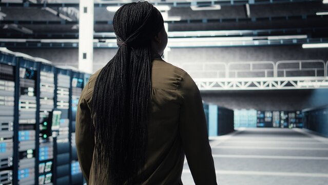 Woman checks server equipment while walking through data center