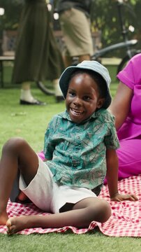 Portrait format: Portrait of joyful parents and boy laughing together on picnic blanket