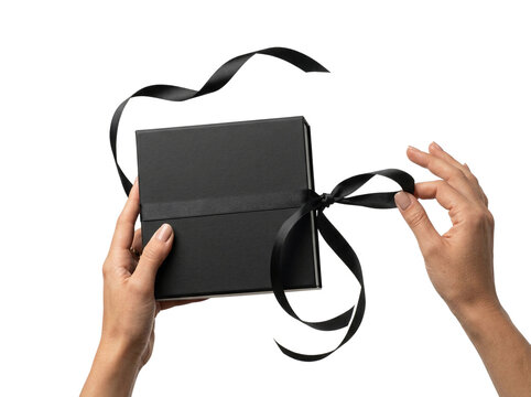 Hands untying black ribbon on elegant gift box, transparent background