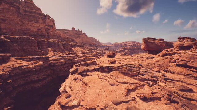 Sunlit canyon rim overlook with sweeping sandstone ridges, warm ochre tones and distant mesas under soft clouds, evocative setting for hiking, outdoor