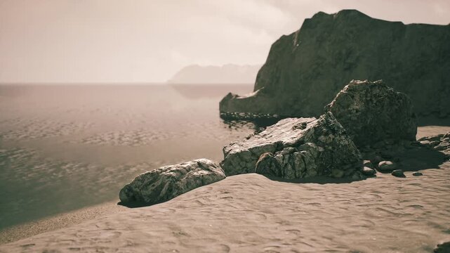 Waves gently lap against the sandy shore while sunlight casts a warm glow over the rocky cliffs. The calm waters reflect the fading light, creating a serene atmosphere.