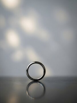 Anillo de plata de estilo minimalista erguido sobre superficie reflectante con fondo bokeh de luces