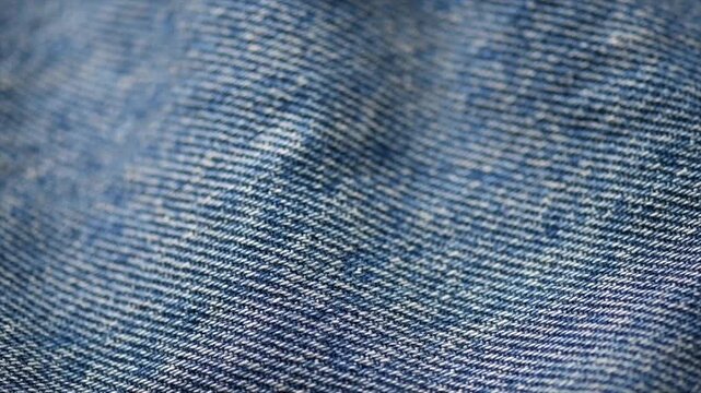 Blue denim cotton jeans fabric texture, jean background, textile backdrop, top view. wallpaper, washed effect jean fabric close up. Rotating, slow motion.  