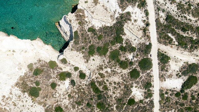 Aerial view of a rocky peninsula surrounded by deep blue water near Mandrakia, Milos, Greece, highlighting the island&rsquo;s dramatic coastal terrain.