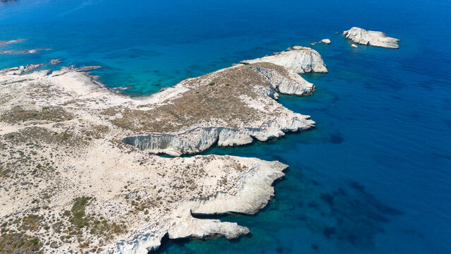 Aerial view of a narrow turquoise inlet cutting through white rock formations near Mandrakia, Milos, Greece.