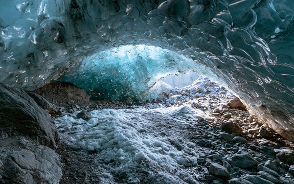 Expansive Ice Cave Interior with Natural Light Illuminating Frozen Walls and Rocky Floor