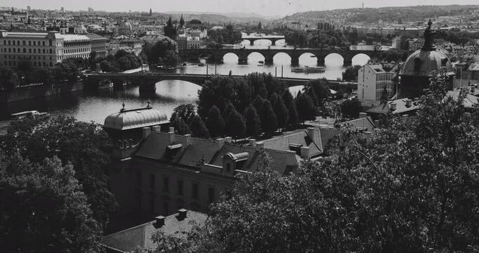 Black and white timelapse view of Vltava River, Charles Bridge in Prague. Archival-style footage featuring vintage film grain, scratches, aged film effects, creating a nostalgic historical atmosphere.