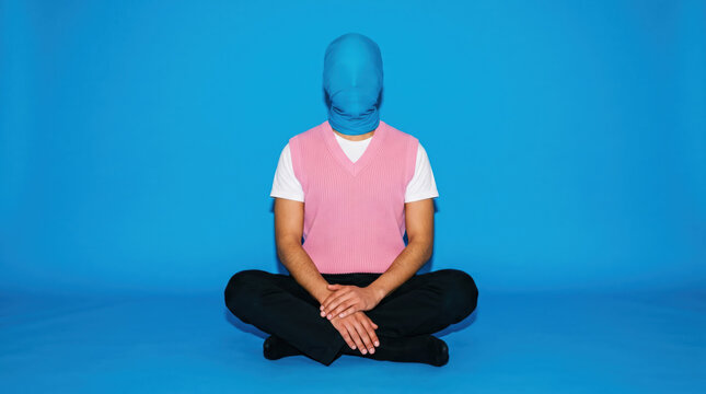 Faceless person seated cross-legged against blue background