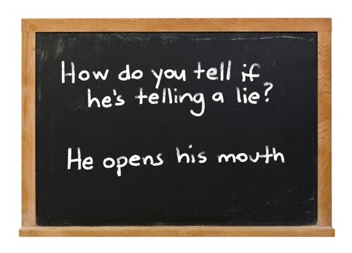 How do you tell if he's telling a lie? He opens his mouth written in white chalk on a black chalkboard isolated in a wooden frame on white