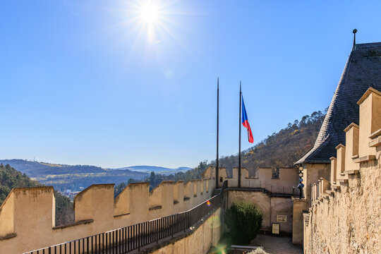 Sunlit view from Karlstejn castle walls with czech flag under clear blue sky