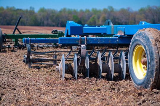 Soil preparation machine. Field tillage machinery. Farm tillage equipment. Agricultural implement. Farming machinery close up. Plowed field equipment. Tilled soil machinery. Rural farm equipment.