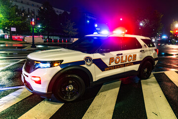 Police SUV on City Street. Emergency Police Lights at Night. Federal Police Patrol Vehicle. Police Car on Wet Street. Law Enforcement SUV at Night. © Svitlana
