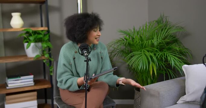 African American woman laughing, holding tablet, answering off-camera question, leaning toward mic
