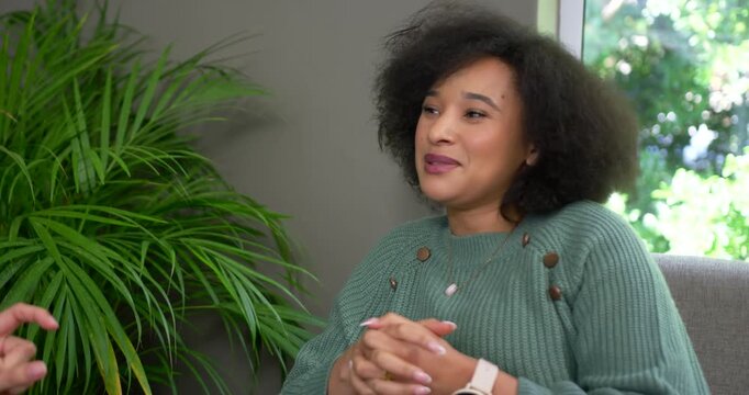 African American woman smiling nodding listening to off-camera speaker in chair green sweater