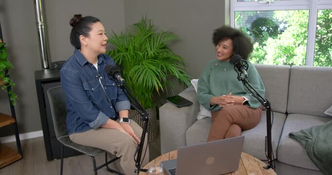Asian woman and African American woman recording while left woman initiating, gesturing at mics