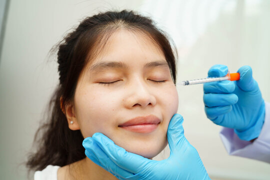 Asian woman receiving lip contouring procedure augmentation performed on face.