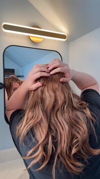 menopausal woman finds and is examining a thinning part line or bald spot in her hair