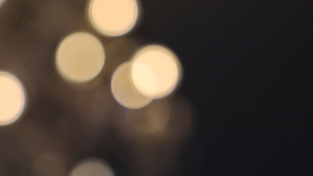 Soft glowing circles create a golden bokeh effect against dark background, offering a cinematic abstract mood with warmth, subtle illumination, and spacious negative space