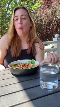 woman eats a bowl of salad on the front porch