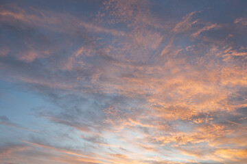 Obraz premium At sunrise or sunset, clouds—streaked with various hues like orange and reddish-yellow—lend a dramatic quality to the sky. 