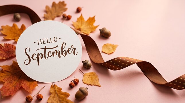 Hello September text is printed on a round card surrounded by autumn leaves and acorns.