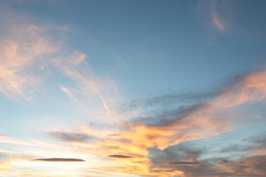 At sunrise or sunset, clouds&mdash;streaked with various hues like orange and reddish-yellow&mdash;lend a dramatic quality to the sky.	