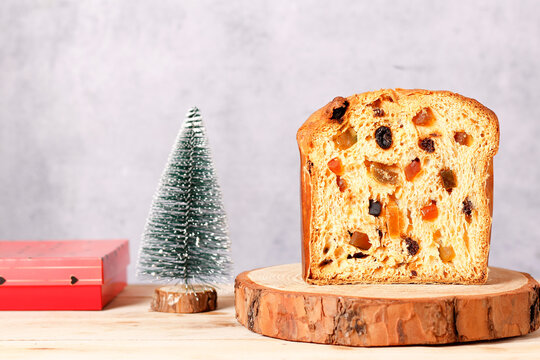 Sliced ​​Christmas panettone with candied fruit and raisins on a rustic wooden base with space for text