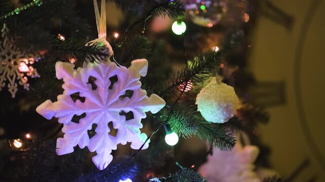 Close-up view of Christmas tree decorations at night with sparkling ornaments, blinking lights, and tinsel creating a festive holiday background.