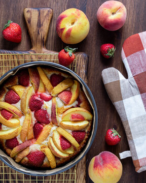 A strawberry peach cake hot out of the oven cooling on a cooling rack.