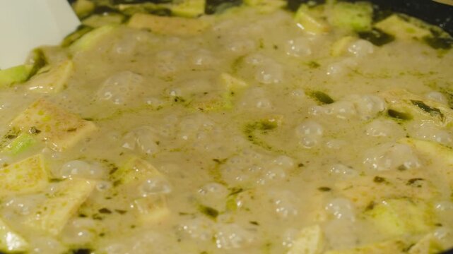 Green curry tofu soup cooking. Thai green curry soup in a white bowl on a white plate with dark background. Flat lay, overhead