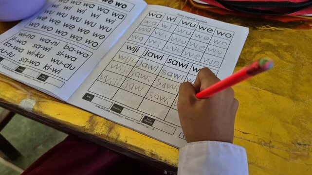 Close up of elementary girl student hands writing alphabet lesson with pencil in workbook