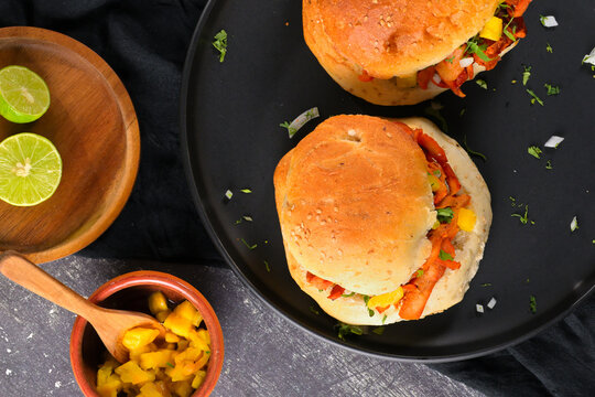 Mexican al pastor sandwich or torta al pastor on a charcoal surface with fresh ingredients like limes and salsa, highlighting authentic cuisine