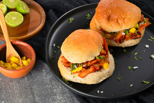 Rustic Mexican al pastor sandwich also known as cemita, full of flavor, with traditional garnishes and side dishes on a dark wooden table