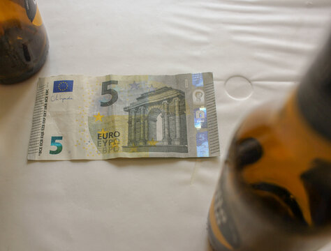 Five Euro Note with Blurred Beer Bottles Conceptualizing Alcohol Expenses in Europe