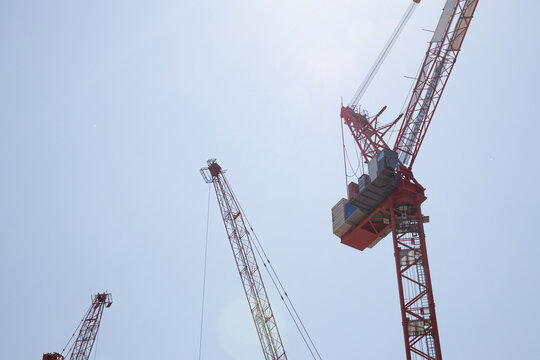 Cranes stand tall against bright sky at building site