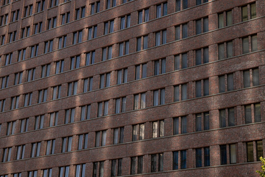 Brick wall of contemporary building showcases large windows reflecting sunlight