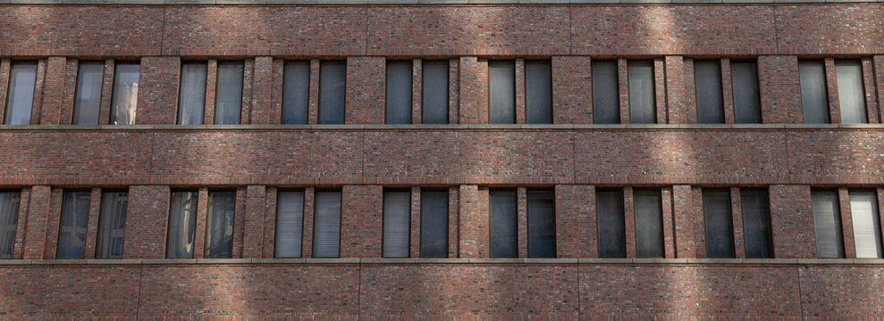 Brick facade displays a series of evenly spaced windows in urban setting
