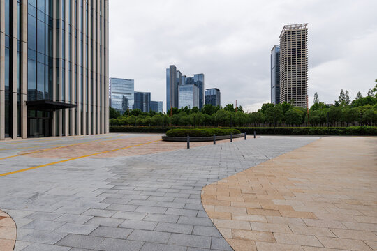 Empty urban plaza with trees and modern skyline