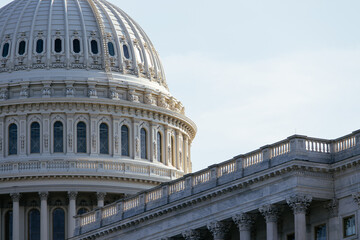 Fototapeta premium United States Capitol building with iconic dome and American flag under clear blue sky in Washington DC, USA. g.
